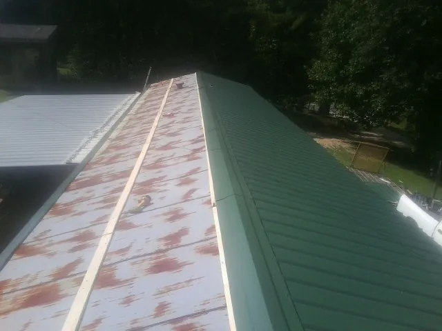 Old rusted panels beside newly installed green metal roofing — Wind Damage Roof Repair by Roofing Brothers in Prophetstown