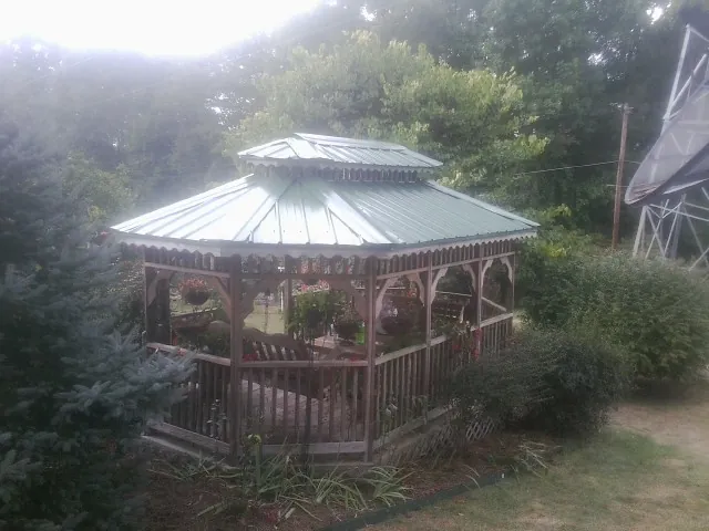 Green metal roof on a backyard gazebo surrounded by garden beds in Prophetstown