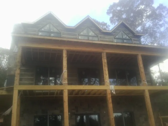 Dormers and porch framing on a large log home under construction — Roof Coating work by our crew in Prophetstown