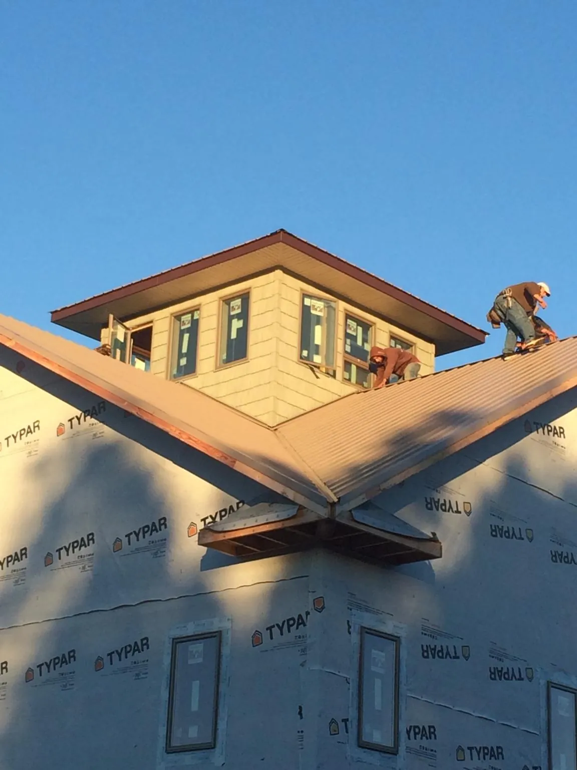 Roofers working around a rooftop cupola on a new metal roof at sunset — Roof Waterproofing in Prophetstown by Roofing Brothers